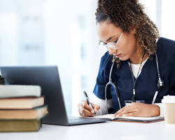 Hình ảnh về Person studying online on a laptop, with nursing books in the background